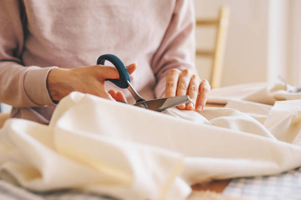 Close up of woman's hand cutting fabric with pinking scissors